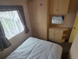 A bedroom with a bed and a wardrobe at Number 186 Owens Caravan Park in Abergele