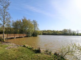 A view of a pond with a wooden bridge at Lodge 5 - Bron Eifion in Criccieth