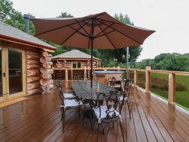 A deck with a table and chairs under an umbrella at Copper Suite in Chulmleigh