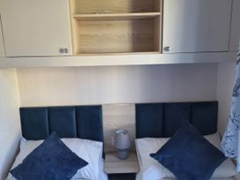 A bedroom with two beds, a lamp, and a shelf at St Andrews Holiday Park - Taigh na Mara, St Andrews