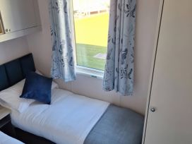 A bedroom with two beds and curtains at St Andrews Holiday Park - Taigh na Mara, St Andrews