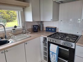 A kitchen with a sink, gas stove, and kettle at St Andrews Holiday Park - Taigh na Mara, St Andrews