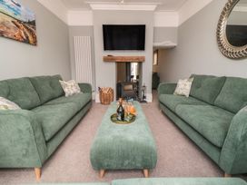 A living room with green sofas and a television at 5 Station Avenue
