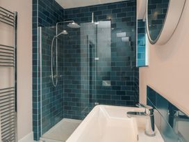 A bathroom with a shower, bathtub and mirror at 5 Station Avenue