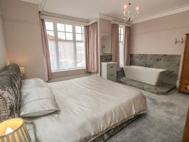 A bedroom with a bed, lamp, and bathtub at 5 Station Avenue