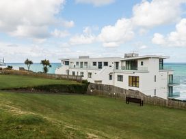 A building near the ocean with grass and a bench at A5 Bay Apt.