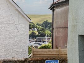 A view between houses showing boats near water at Tiller Cottage in Dartmouth