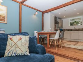 A dining room with a table and chairs adjacent to a kitchen at Tiller Cottage in Dartmouth