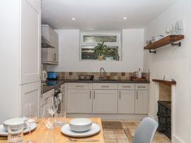 A kitchen with cabinets, stove, sink, and dining set at Tiller Cottage in Dartmouth