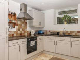A kitchen with cabinets, cooker, kettle, and sink at Tiller Cottage in Dartmouth