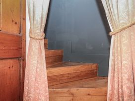 A staircase with wooden steps and curtains at Tiller Cottage in Dartmouth