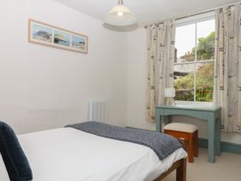 A bedroom with a bed and window at Tiller Cottage in Dartmouth