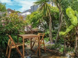 A garden with a table and chairs surrounded by plants at Tiller Cottage in Dartmouth