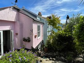 An outdoor view of a pink house with garden features at Tiller Cottage in Dartmouth