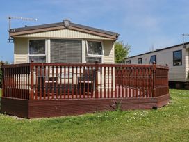 A mobile home with a deck and grass at Beech Lodge in Wadebridge