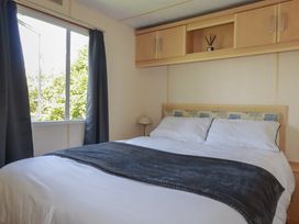 A bedroom with a bed and a window at Beech Lodge in Wadebridge