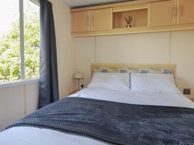 A bedroom with a bed and bedside lamp at Beech Lodge in Wadebridge