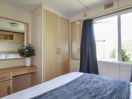 A bedroom with a bed, wardrobe, and flowers at Beech Lodge in Wadebridge