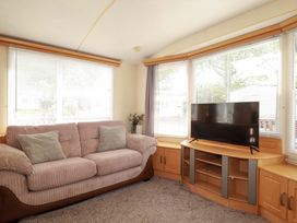 A living room with a sofa and television at Beech Lodge Wadebridge