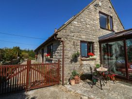 An outdoor view of a stone house with a gate and table at Dunvant in Swanage