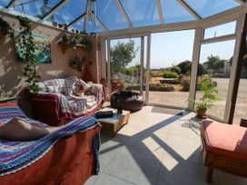 A conservatory with seating and plants at Dunvant in Swanage