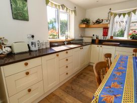 A kitchen with cabinets, sink, and a table at Dunvant in Swanage