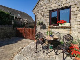 An outdoor seating area with a stone wall and flower pots at Dunvant in Swanage
