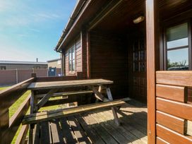An outdoor area with a wooden table and benches at Lodge 4 - Bron Eifion Criccieth