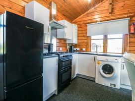 A kitchen with refrigerator, stove, microwave, and washing machine at Lodge 6 - Sleep 4 - Twin and Double, Criccieth