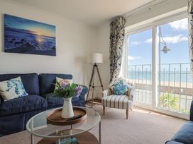 A living room with a sofa, table, and view of the sea at 2 Lyme Mews Seaton