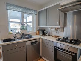 A kitchen with a sink, dishwasher, stove, and kettle at 2 Lyme Mews Seaton