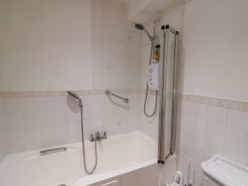 A bathroom with a bathtub and shower at 2 Lyme Mews Seaton