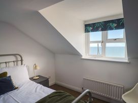 A bedroom with a bed and window overlooking the sea at 2 Lyme Mews in Seaton