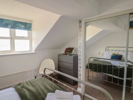 A bedroom with a bed, nightstand, and window at 2 Lyme Mews, Seaton