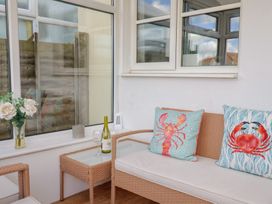 A conservatory with wicker furniture and decorative items at 2 Lyme Mews Seaton