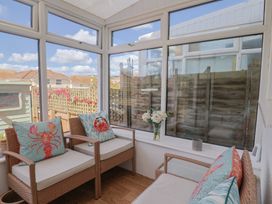 A conservatory with rattan chairs and flowers at 2 Lyme Mews Seaton