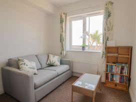 A living room with a sofa, table and bookshelf at 2 Lyme Mews in Seaton
