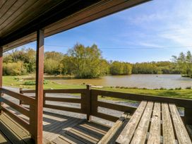 A view of a lake and trees from a wooden deck at Lodge 9 - Sleep 4 - Double and Twin in Criccieth