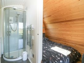 A shower and a bedroom with wood paneling at Bron Eifion Pod 3 Criccieth