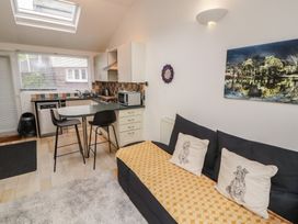 A kitchen area with a couch and bar stools at Juniper Hayloft in Ambleside