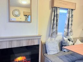A living room with a mirror, clock, and sofa at Skipsea sands holiday park in Driffield