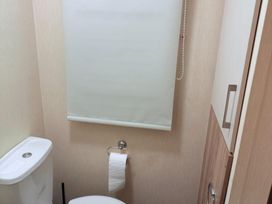 A bathroom with a toilet and a toilet paper holder at Skipsea sands holiday park in Driffield