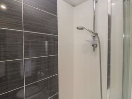 A shower with a showerhead and wall tiles at Swan Haven in Grange-Over-Sands