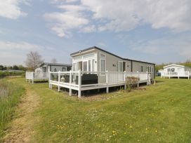 A mobile home with a deck situated near a lake at Swan Haven in Grange-Over-Sands