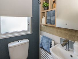 A bathroom with a toilet, sink, and shelving at Santa Maria in Llandysul