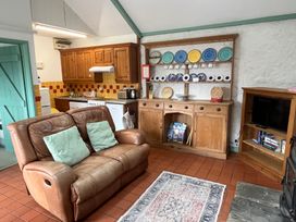 A living room with a sofa and kitchen units at Starling Cottage near Cowbridge