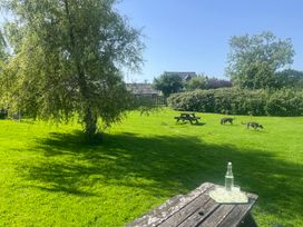 A garden with a picnic table and dogs at Starling Cottage near Cowbridge