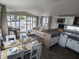 A living room and kitchen with a sofa and dining area at 025 Maes Glas in Prestatyn