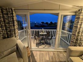 A seating area with a table and chairs overlooking the outdoor area at 025 Maes Glas in Prestatyn