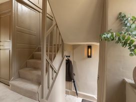 A staircase with a coat and umbrella in a hallway at Church Alley House Stow-On-The-Wold